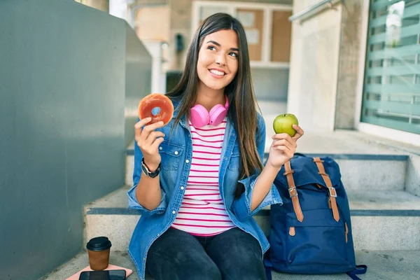 Νεαρή Ισπανίδα Μαθήτρια Χαμογελά Χαρούμενη Κρατώντας Ντόνατ Και Πράσινο Μήλο — Φωτογραφία Αρχείου