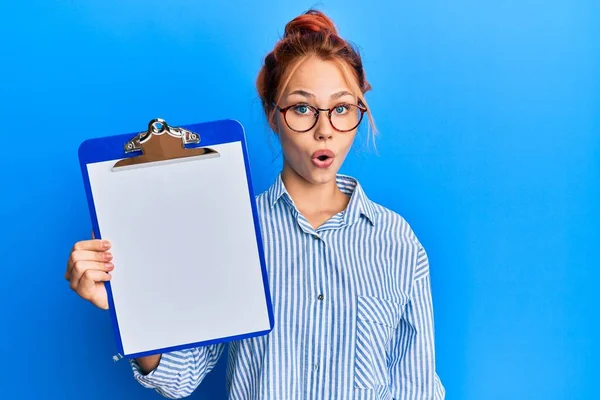 Young Redhead Woman Holding Clipboard Blank Space Scared Amazed Open — Stock Photo, Image