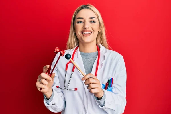 Νεαρή Καυκάσια Γυναίκα Στολή Γιατρού Κρατώντας Ένα Διαπασών Χαμογελώντας Ένα — Φωτογραφία Αρχείου