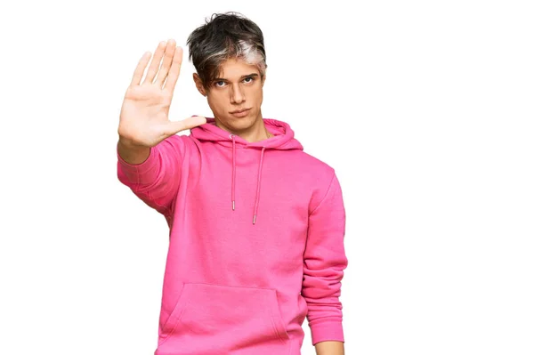年轻的惊慌失措的男人穿着宽松的粉色运动衫 用手拍着手停止歌唱 用消极而严肃的手势警告人 — 图库照片