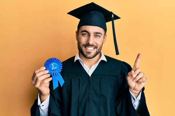 Jovem Hispânico Vestindo Roupão Formatura Segurando Emblema Lugar Sorrindo Feliz — Fotografia de Stock