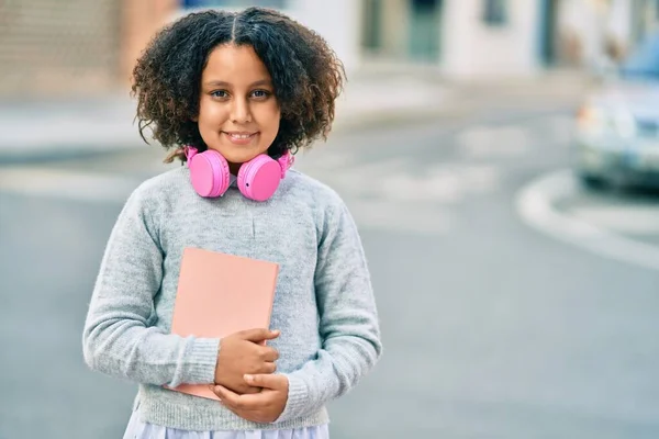 Adorável Estudante Hispânico Menina Segurando Livro Usando Fones Ouvido Cidade — Fotografia de Stock