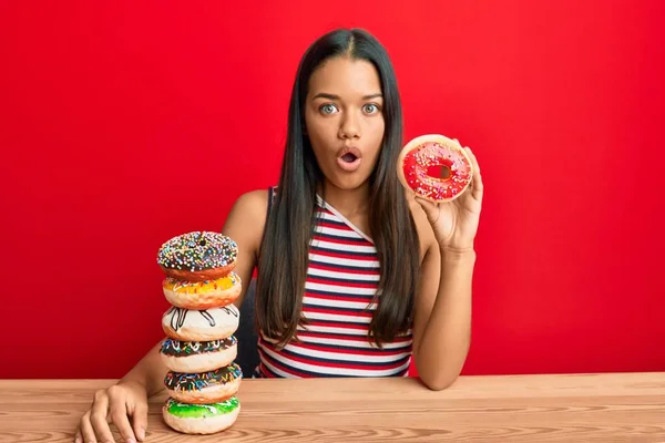 Hermosa Mujer Hispana Sosteniendo Sabrosas Rosquillas Coloridas Asustadas Sorprendidas Con —  Fotos de Stock