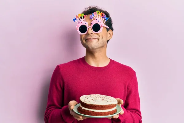 Przystojny Latynos Śmiesznych Urodzinowych Okularach Trzymający Tort Uśmiechem Boku Patrzący — Zdjęcie stockowe
