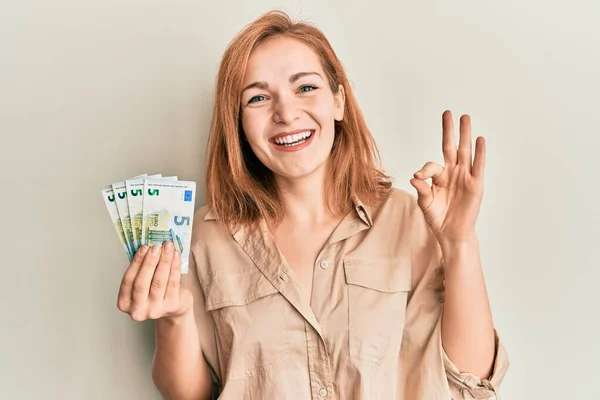 Młoda Kaukaska Kobieta Trzyma Kilka Banknotów Euro Robi Znak Palcami — Zdjęcie stockowe