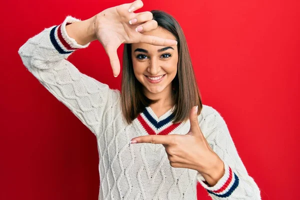 若いブルネットの女の子は幸せな顔で手と指でフレームを作る笑顔カジュアルな学生セーターを着ています 創造性と写真の概念 — ストック写真