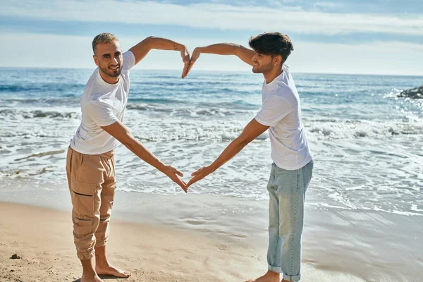 Genç Eşcinsel Çift Gülümseyerek Kumsalda Kollarıyla Kalp Sembolü Yapıyor — Stok fotoğraf