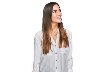 Gündelik giysiler giyen genç ve güzel bir kadın yüzünde gülümseme, doğal bir ifade ile yan yana bakıyor. Kendinden emin gülen. 