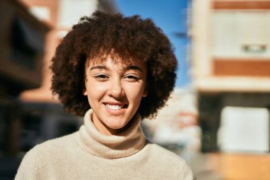 Genç İspanyol kız gülümseyerek şehirde mutlu mesut dikiliyor..