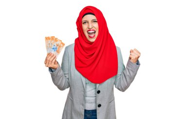 İslami başörtüsü takan güzel İspanyol kadın elinde 10 İsviçre frangı banknotla gururla bağırıyor, zaferi ve başarıyı kutluyor. 