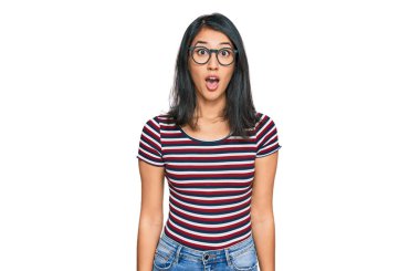 Güzel Asyalı genç bir kadın günlük kıyafetler ve gözlük takıyor. Şaşırmış ve korkmuş bir ifade, korku ve heyecanlı bir yüz ifadesi var.. 