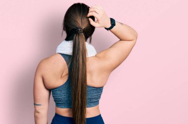 Spor kıyafetleri giyen ve havluyu ters takan genç İspanyol kız elleri kafasında şüpheyi düşünüyor. 