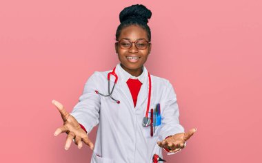 Genç Afro-Amerikan kadın doktor üniforması ve steteskop giymiş neşeli gülümseyerek yardım eli uzatıyor ve kabul ediyor.. 