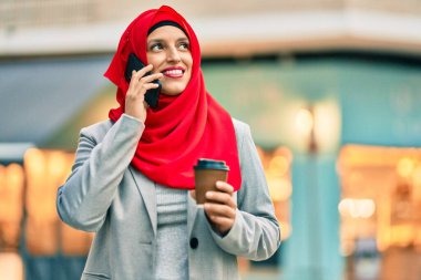 Genç Arap iş kadını akıllı telefondan konuşuyor ve şehirde kahve içiyor..