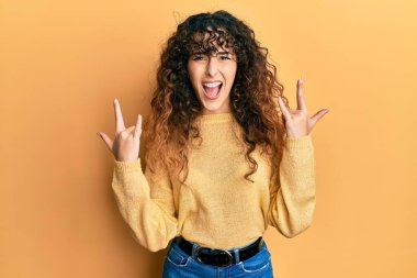 Günlük kıyafetler giymiş, çılgın bir ifadeyle bağıran genç İspanyol kız elleri havada rock sembolü yapıyor. Müzik yıldızı. ağır kavram. 