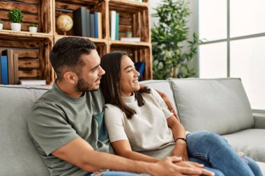 Kanepede oturan genç latin çift evde sarılıyorlar..