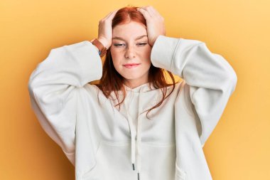 Başağrısı, acı ve migren yüzünden çaresiz ve stresli olan sıradan bir kazak giyen genç kızıl saçlı kız. Eller başının üstünde.. 