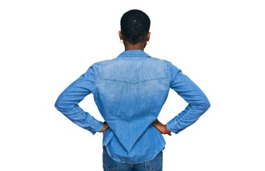 Genç Afro-Amerikalı kadın gündelik giysiler giyip arkasını dönüp kollarını bedeninden ayırıyor. 