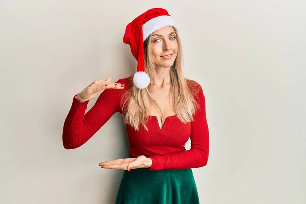 美丽的高加索女人 身穿圣诞服装 头戴帽子 手握大而大的标志和尺寸符号 微笑着看着摄像机 计量概念 — 图库照片