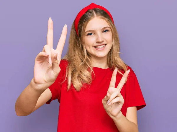 티셔츠를 아름다운 코카서스 소녀는 카메라 앞에서 손가락 승리의 표시를 바라보며 — 스톡 사진