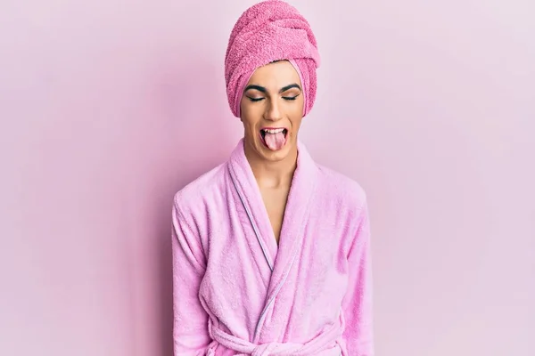 年轻男子头戴浴巾 身穿浴衣 化装打扮成女人 带着滑稽的表情伸出舌头 情感概念 — 图库照片