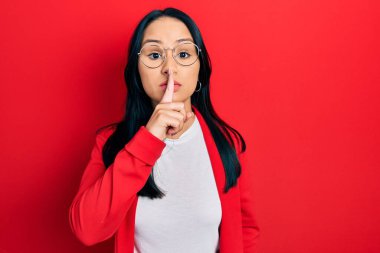 Burnunda piercing olan, sıradan bakışlar ve gözlük takan dudaklarında parmak olan güzel İspanyol kadın sessiz olmak istiyor. sessizlik ve gizli konsept. 