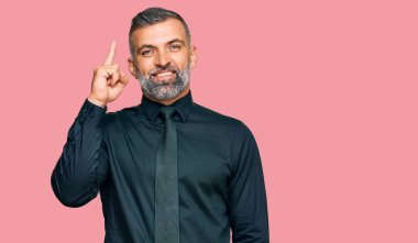 İş kıyafetleri giymiş orta yaşlı yakışıklı bir adam başarılı bir fikri işaret ediyor. Heyecanlı ve mutlu. Bir numara.. 