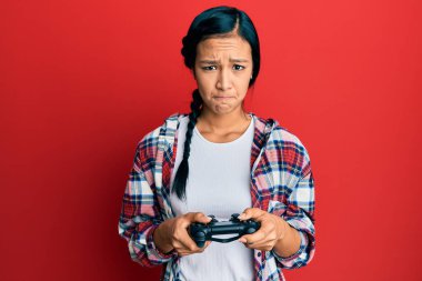 Güzel İspanyol kadın video oyunu oynuyor. Kontrolcü, şüpheci ve gergin. Sorun yüzünden surat asıyor. negatif kişi. 