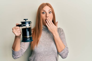 Fransız kahve makinesini tutan genç İrlandalı kadın ağızını eliyle kapatıyor, şaşırmış ve hata yapmaktan korkuyor. şaşırmış ifade 