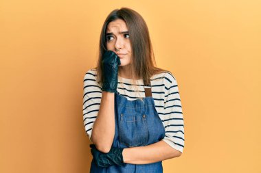 Berber önlüğü giyen genç İspanyol kadın gergin ve gergin görünüyor. Ağzı tırnak yiyen ellerle. anksiyete. 