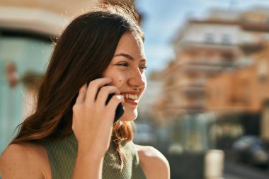 Beyaz kız gülümsüyor. Şehirdeki akıllı telefondan konuşuyor..