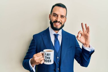 Sakallı genç adam patron kahve fincanından içiyor. Parmaklarıyla imza atıyor, gülümsüyor. Mükemmel bir sembol. 