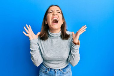 Kafkasyalı genç kadın balıkçı yaka kazak giyiyor. Yan tarafa bakıyor, rahat profil pozu veriyor. Kendine güvenen bir gülümsemesi var.. 