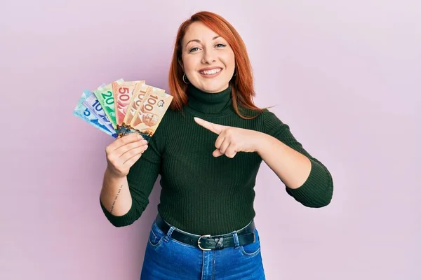 Mulher Ruiva Bonita Segurando Dólares Canadenses Sorrindo Feliz Apontando Com — Fotografia de Stock
