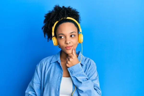 年轻的非洲裔美国女孩 一边用耳机听音乐 一边认真地思考着手托着下巴的问题 思考着令人困惑的想法 — 图库照片