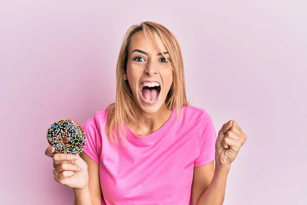 Hermosa Mujer Rubia Sosteniendo Rosquilla Gritando Orgullosa Celebrando Victoria Éxito —  Fotos de Stock