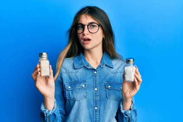 Mujer Caucásica Joven Sosteniendo Salero Cara Choque Mirando Escéptico Sarcástico —  Fotos de Stock