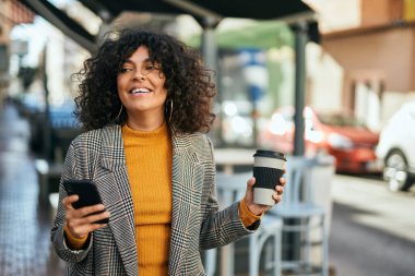 Genç İspanyol iş kadını akıllı telefon kullanıyor. Şehirde kahve içiyor..