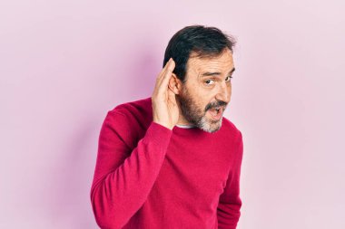 Orta yaşlı İspanyol bir adam, günlük giysiler giymiş, ağzı kulaklarına varan bir gülümsemeyle dedikoduları ve dedikoduları dinliyor. Sağırlık kavramı. 