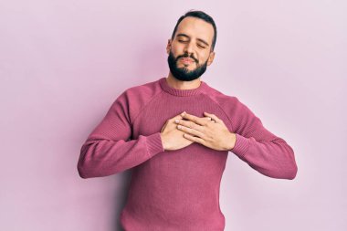 Sakallı, sıradan bir süveter giyen, elleri göğsünde, gözleri kapalı, yüzünde minnet ifadesi olan genç bir adam. sağlık kavramı. 