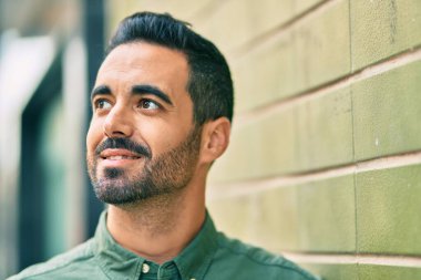 Genç İspanyol adam gülümseyerek şehirde mutlu mesut dikiliyor..