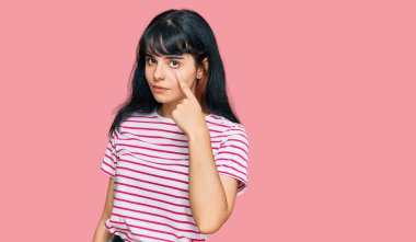 Gündelik kıyafetler giyen genç İspanyol kız senin jestini ve şüpheli ifadesini izleyerek gözüne işaret ediyor. 