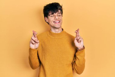 Sarı süveter giyen yakışıklı hippi genç adam umut ve gözler kapalı gülümseyerek el işareti yapıyor. Şans ve batıl inançlar. 