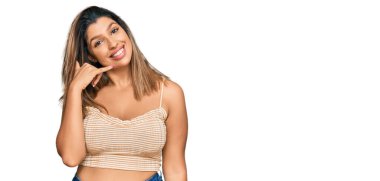 Güzel esmer kadın günlük kıyafetler giyip gülümsüyor telefonla el ve parmaklarıyla jest yapıyor telefonda konuşuyor gibi. iletişim kavramları. 