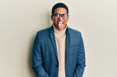 Zarif kıyafetler giyen ve gözlük takan yakışıklı İspanyol adam komik bir ifadeyle dilini dışarı çıkartıyor. duygu kavramı. 