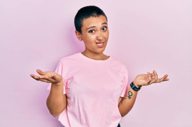 Kısa saçlı, sıradan pembe tişörtlü güzel bir İspanyol kadın. Hiçbir şeyden habersiz ve kolları açık, hiçbir fikri yok.. 