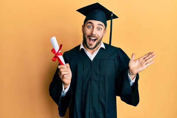 Jovem Hispânico Vestindo Roupão Formatura Segurando Diploma Celebrando Realização Com — Fotografia de Stock