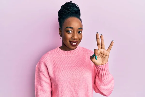 身穿休闲式冬季毛衣的年轻的非洲裔美国女人 带着自信和快乐的笑容 手指头指向三号 — 图库照片