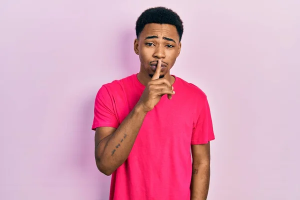 若いアフリカ系アメリカ人の男性は 唇に指で静かになるように求めてカスアキャストシャツを着て 沈黙と秘密の概念 — ストック写真