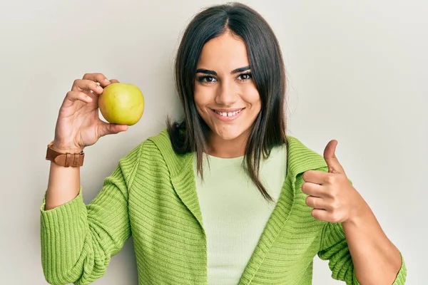 Mladá Brunetka Žena Drží Zelené Jablko Úsměvem Šťastný Pozitivní Palec — Stock fotografie